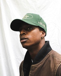 a young man wearing a green baseball cap