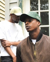 two men standing next to each other in front of a house